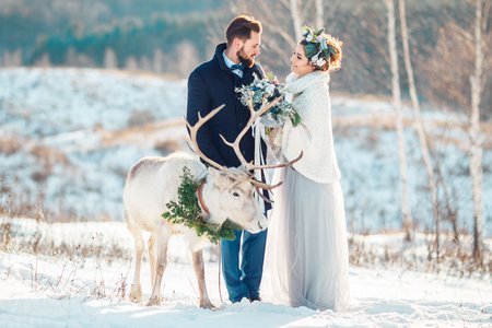 Braupaar im Freien bei einer Winterhochzeit mit einem weißen Hirsch