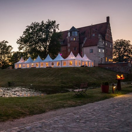 Aussenansicht der Hochzeitslocation Schloss & Gut Ulrichshusen mit See und Schloss bei Abenddämmerung