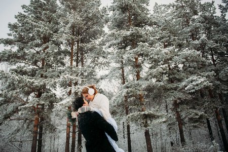 Hochzeitspaar im Winter mit verschneiten Wald
